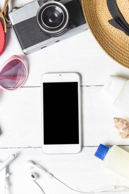 Plaj aksesuarları. Çanta, havlu, güneş gözlüğü ve ahşap arka plan üzerinde parmak arası terlik. Kopya alanı ile Üstten Görünüm