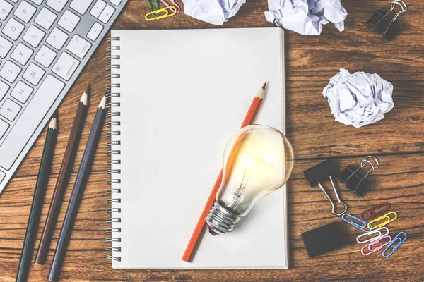 しわくちゃの事務用紙とテーブルの上に電球立って素晴らしいアイデア コンセプト — ストック写真