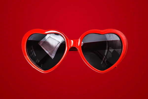 Red sunglasses on red background