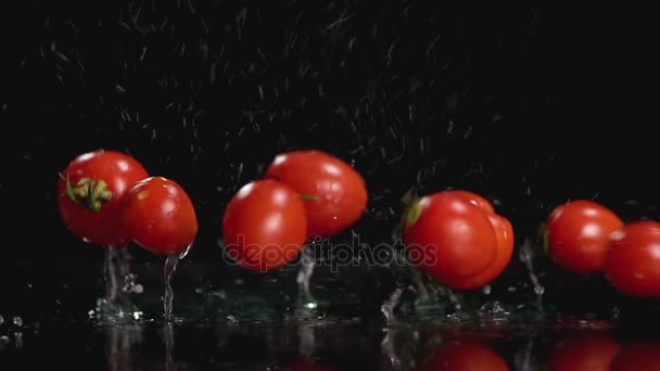 Zpomalený pohyb rajčat ve vodě na tmavém pozadí s kopií prostor