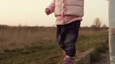 Kız bebek tutun onu anneler el ve kaldırım boyunca yürüyüş
