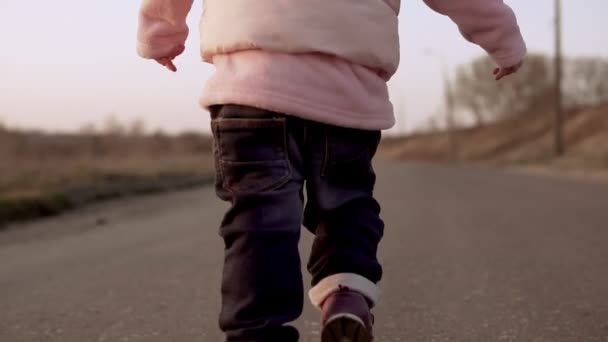 Beine in Jeans eines kleinen Mädchens, das bei Sonnenuntergang in Zeitlupe läuft — Stockvideo