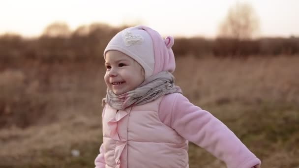 Little girl running and laughing at sunset in slow motion in pink clothing — Stock Video