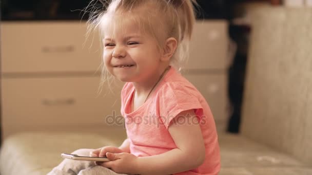 Lilla baby flicka som leker med telefonen hemma. UHD skott. — Stockvideo
