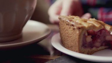 Eller, çay ve dilim kek close-up. Kadın cafede pasta yemeye