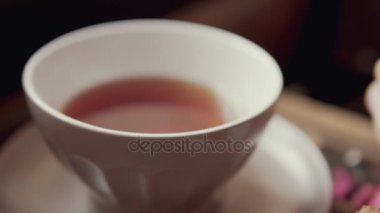 Eller, çay ve dilim kek close-up. Kadın cafede pasta yemeye
