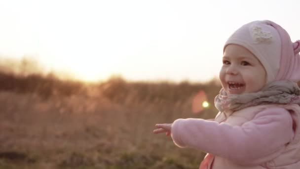 Kleines Mädchen läuft und lacht bei Sonnenuntergang in Zeitlupe in pinkfarbener Kleidung — Stockvideo