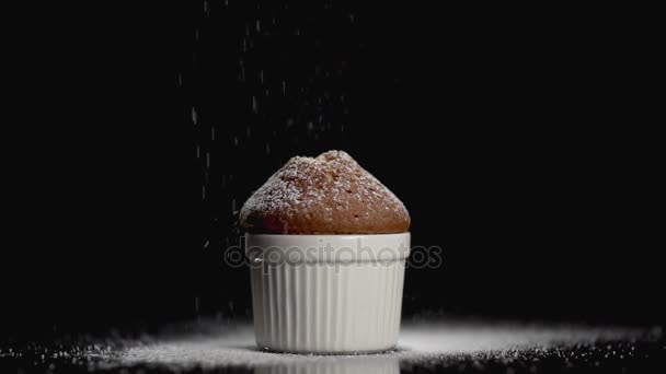 Dort posypeme muffin s moučkovým cukrem na černém pozadí s copyspace — Stock video