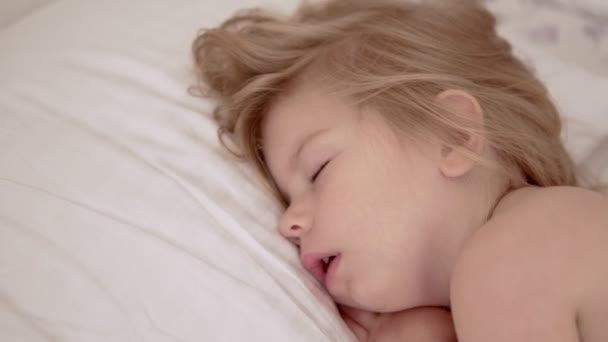 特写熟睡的婴儿女孩在枕头上。在 4k 到光场景 — 图库视频影像