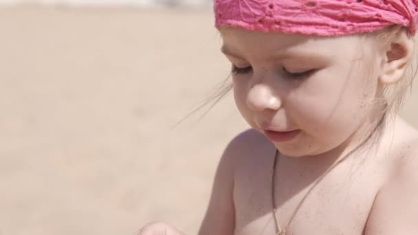 Niña linda jugando con arena y conchas marinas en la playa. De cerca en UHD — Vídeos de Stock