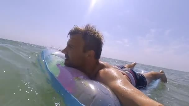 Mladý šťastný muž relaxační na nafukovací matraci v moři — Stock video