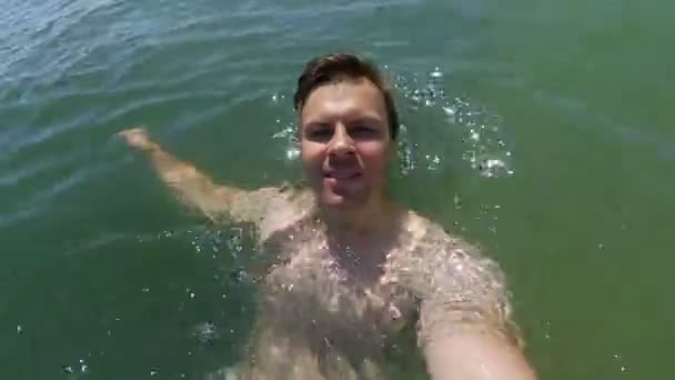 Mladý atletický muž že selfie v moři a plave na zadní straně — Stock video