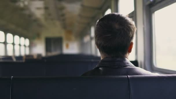年轻男子坐着，看着通过移动的火车窗外独自到视图 — 图库视频影像