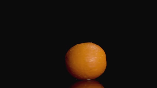 Slo-motion laranja torção no fundo escuro no centro com espaço de cópia — Vídeo de Stock