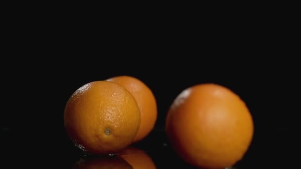 Movimento lento de laranjas caindo no fundo escuro com espaço de cópia na parte superior — Vídeo de Stock