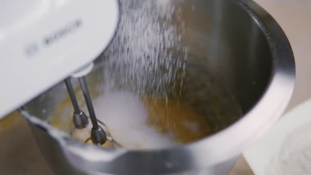 El confitero mezcla las yemas de huevo y el azúcar en un recipiente de metal. Primer plano en cámara lenta — Vídeo de stock