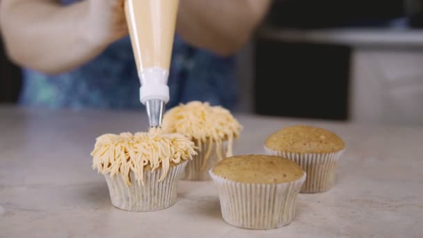 Decorar magdalenas con crema de naranja. Con la bolsa de cocina confitero hacer magdalena — Vídeo de stock