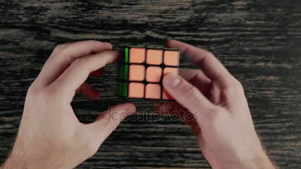 Minsk, Wit-Rusland - 20 November 2017: Jongens handen oplossen van Rubiks kubus. Bovenaanzicht — Stockvideo