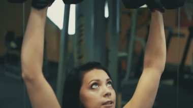 Genç kadın fitness salonunda dumbbells ile yapıyor. Sağlıklı yaşam tarzı