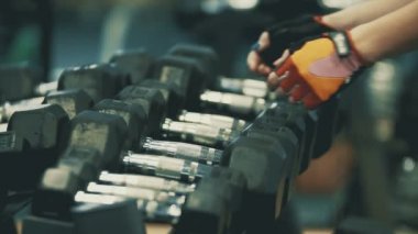 Kadın atlet ağır dumbbells alarak elleri. Egzersiz için hazırlanıyor