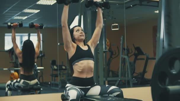 Young woman doing exercises with dumbbells in fitness gym. Healthy lifestyle — Stock Video
