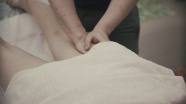 Güzellik spa merkezinde masaj ayak olan genç bir kadın. Ayak ve bacak masör kneads.