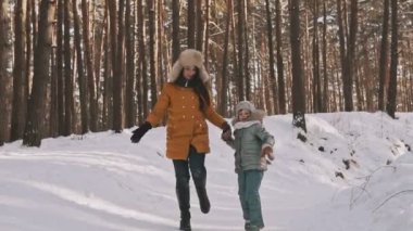 Mutlu anne ve kızı gülen ve kış orman yavaş atlama
