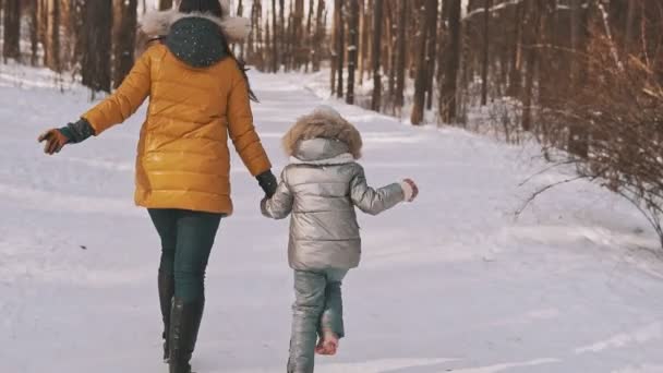 Счастливые мать и дочь смеются и веселятся в зимнем лесу в медленном движении — стоковое видео