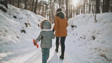 Arkadan Görünüm anne ve kızı kış Parkta yürümek. Ağır çekimde aile eğlence