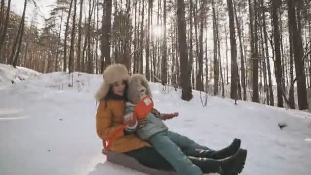 Joven madre e hija divirtiéndose en trineo en parque de invierno en slomo — Vídeo de stock