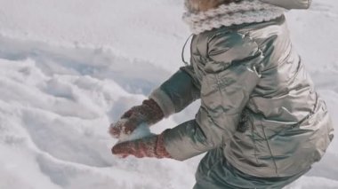 Kar kızı yavaş hareket ile oynarken annesi. Aile var eğlenceli kış günü