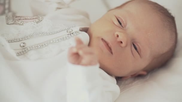 Lindo bebé recién nacido en ropa blanca mirando la cámara — Vídeos de Stock