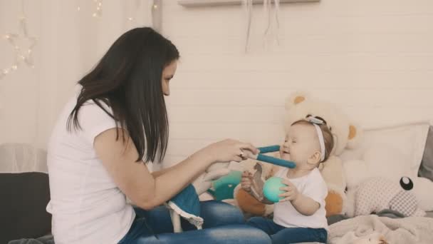 Jovem mãe e filha se divertindo no quarto com brinquedo de pelúcia em câmera lenta — Vídeo de Stock