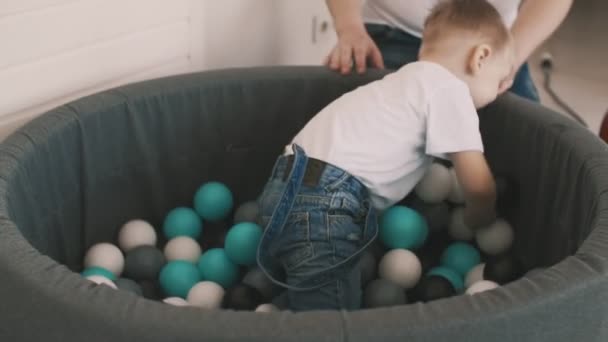 Mały chłopiec z ojcem bawić się w basenie kolorowe kulki — Wideo stockowe