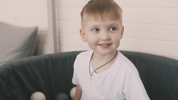 Smiling boy play in pool of coloured balls — Stock Video