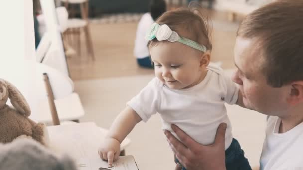 Kleine Tochter in den Armen des Vaters zu Hause. Lächelnder Vater mit Kind — Stockvideo