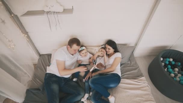 Glückliche Familie genießt auf dem Bett. junge Familie haben Spaß drinnen. Familienkonzept — Stockvideo