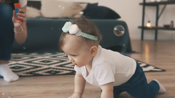 Little baby girl crawling on the floor in the room with young mother and brother — Stock Video