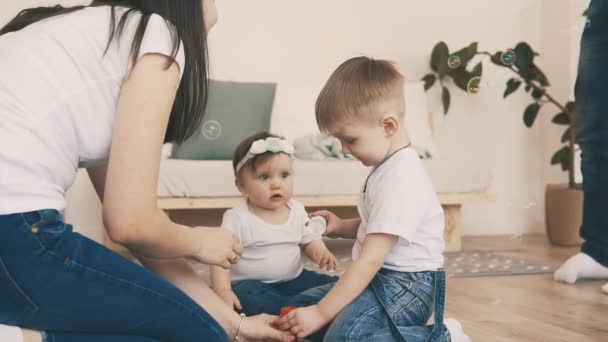 Pequeño hijo en jeans y camiseta blanca tratar de hacer burbujas con la madre joven — Vídeo de stock