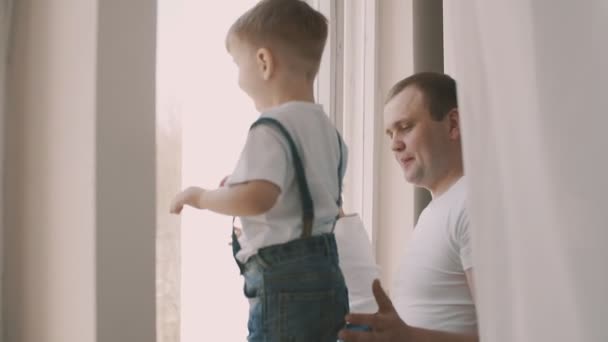 Young father standing near window with his cute daughter and son in slomo — Stock Video