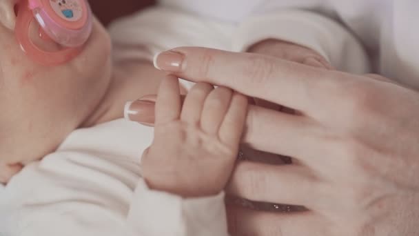 Новорожденный держит матерей за руку. Закрыть в замедленной съемке — стоковое видео