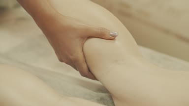 Güzellik spa merkezinde masaj ayak olan genç bir kadın. Ayak ve bacak masör kneads.