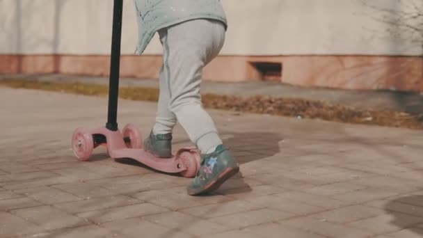 Счастливая девушка едет на розовом скутере на открытом воздухе в солнечный день в замедленной съемке — стоковое видео