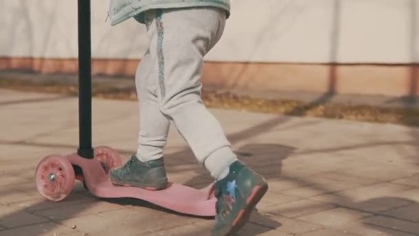 Glückliches Mädchen fährt bei sonnigem Tag auf rosa Roller im Freien in Zeitlupe — Stockvideo