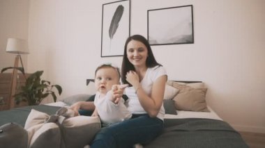 Genç anne ve sevimli kızı yatak odasında, yavaş hareket eğleniyor
