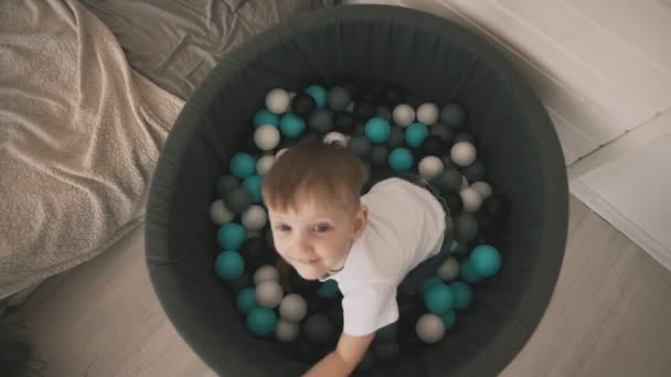 Menino jogar na piscina de bolas coloridas — Vídeo de Stock