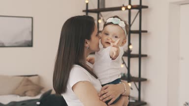 Küçük kızı evde anneler kollarında. Bebek annesiyle gülen