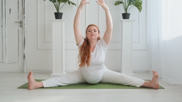 Ung kvinna i vita kläder som sträcker sig. Gravid kvinna som utövar yoga i 4k — Stockvideo