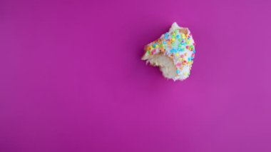 Pembe arka planda donut ısırığı hareketini durdurun. Lezzetli donut yemek, zaman aşımı