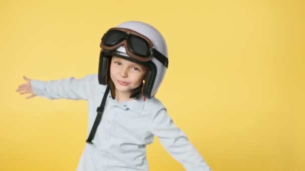 Malý chlapec nosí bílou helmu a pilotní brýle na žlutém pozadí. — Stock video